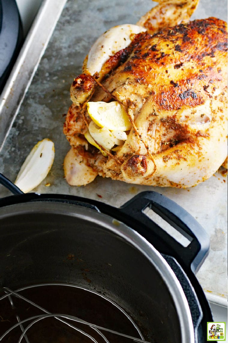 Cooked roasted chicken on a baking sheet next to a pressure cooker
