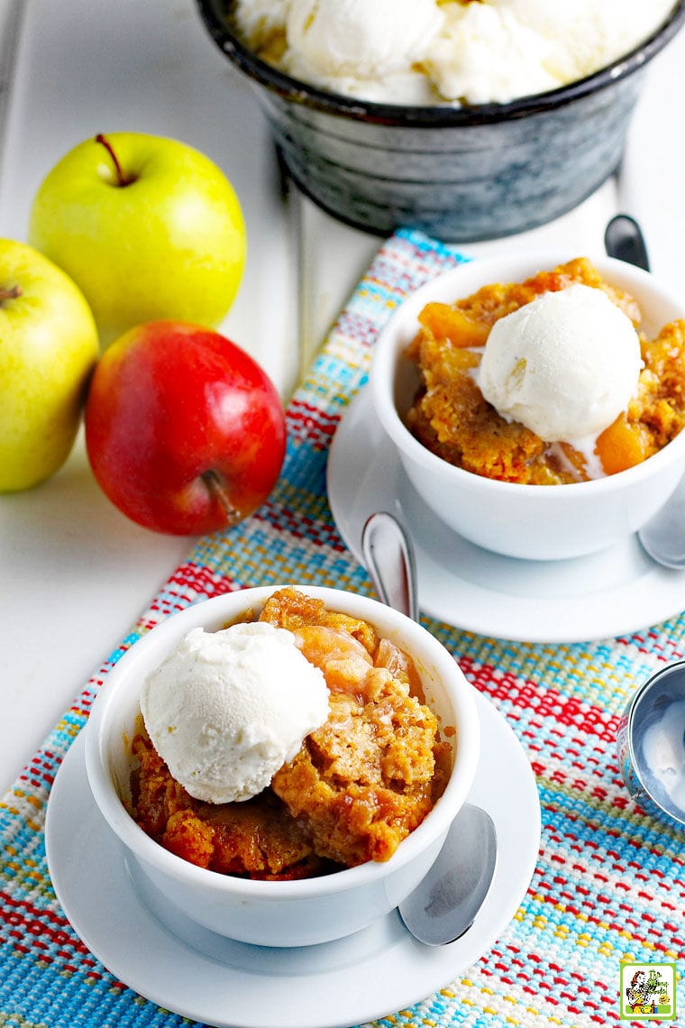 Dishes of Crockpot Apple Cobbler with scoops of vanilla ice cream.