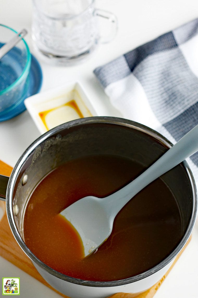 Stiring caramel sauce with a grey spatula in a saucepan.