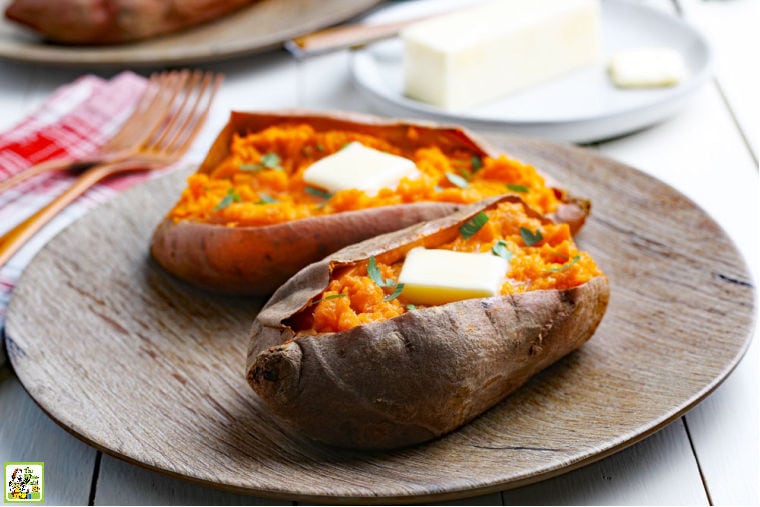 A brown plate with two Instant Pot Sweet Potatoes with pats of butter, forks, and napkins.