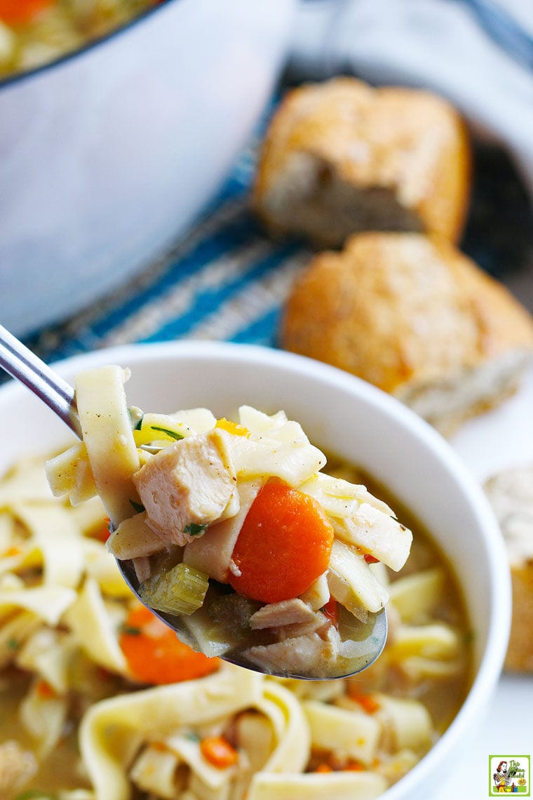 A spoon and bowl of Turkey Soup with bread and a Dutch oven stock pot in the background.