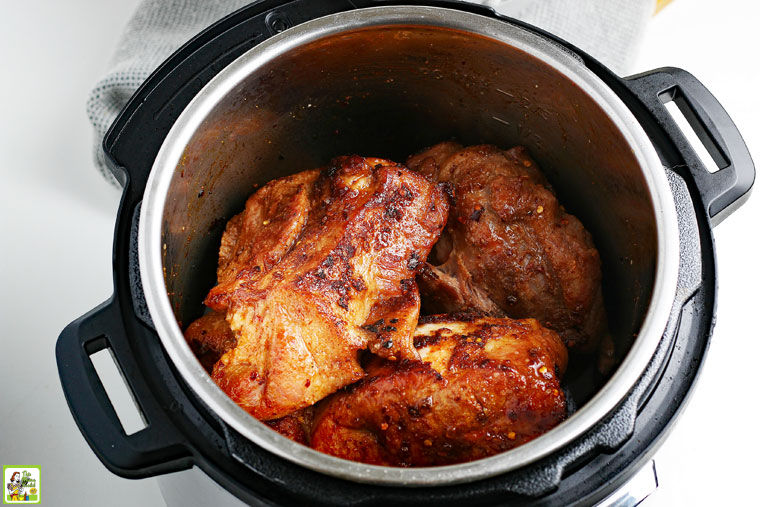 Open Instant Pot with pieces of cooked pulled pork.