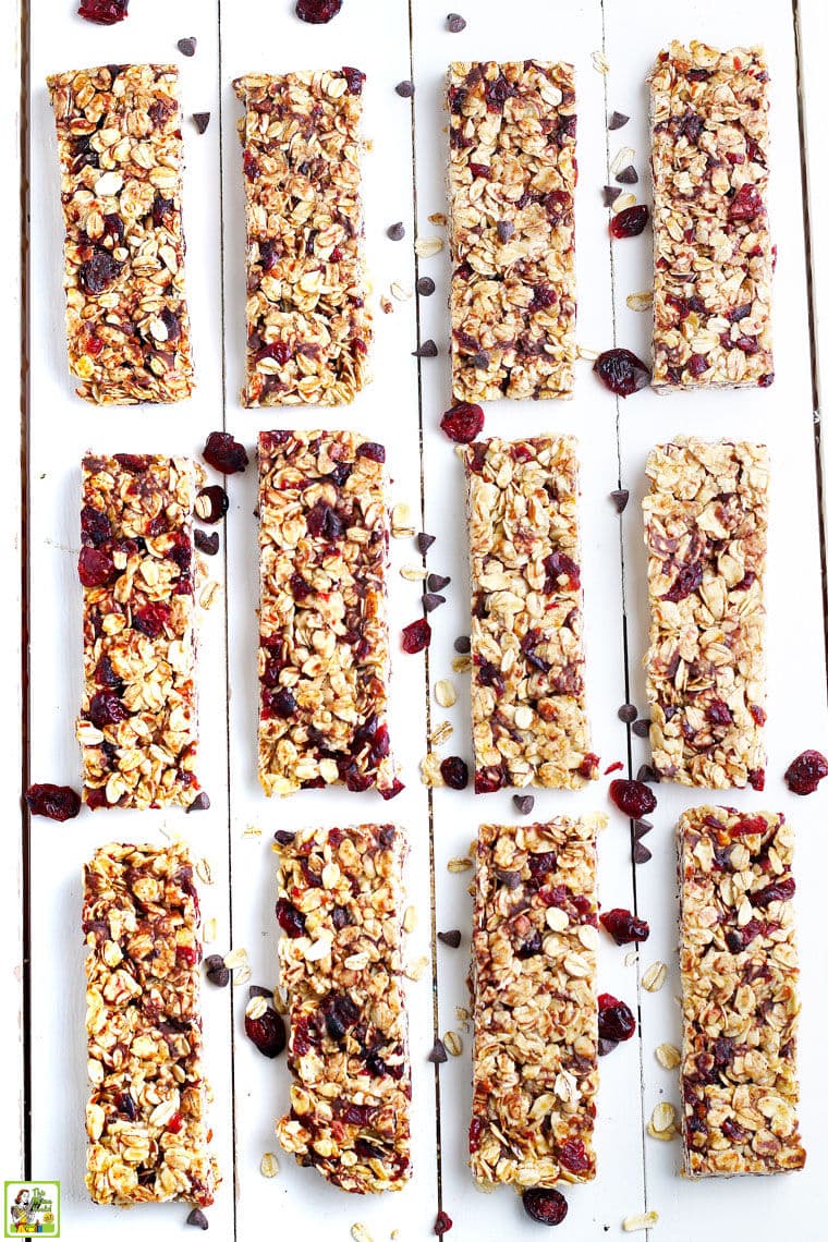 Homemade granola bars made with chocolate chips, oatmeal, and dried cranberries on a white wooden board.