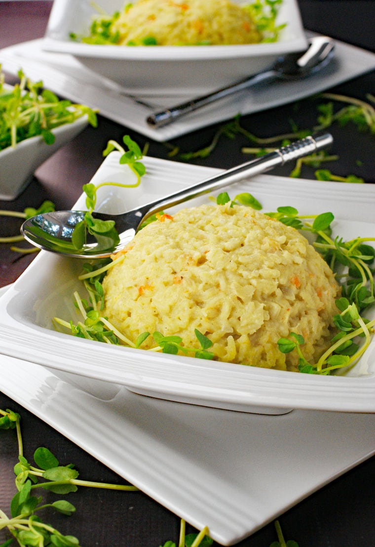 White bowls of seafood risotto with silver spoons.