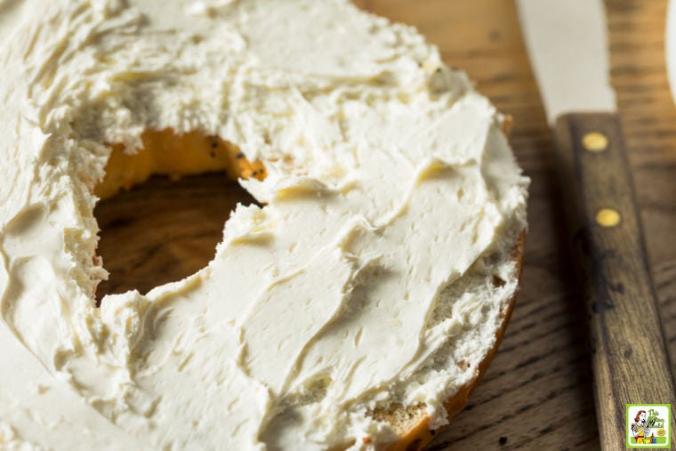  nærbillede af en flødeost dækket bagel og en kniv.