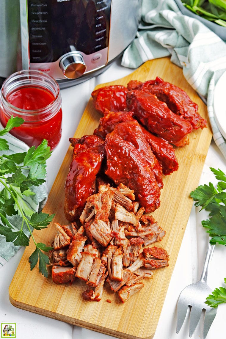Instant Pot barbecue country style ribs wooden cutting board, a jar of BBQ sauce, and a serving fork.