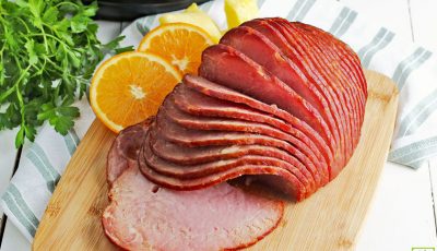Spiral Instant Pot Ham on a wooden cutting board with orange slices.