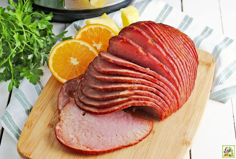 Spiral Instant Pot ham on a wooden cutting board with orange slices.