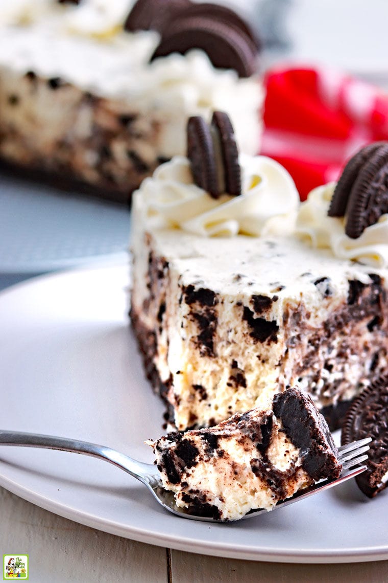 Piece of a Oreo cheesecake on a fork on a plate with a slice of cheesecake.