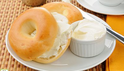A sliced bagel with cream cheese and coffee.