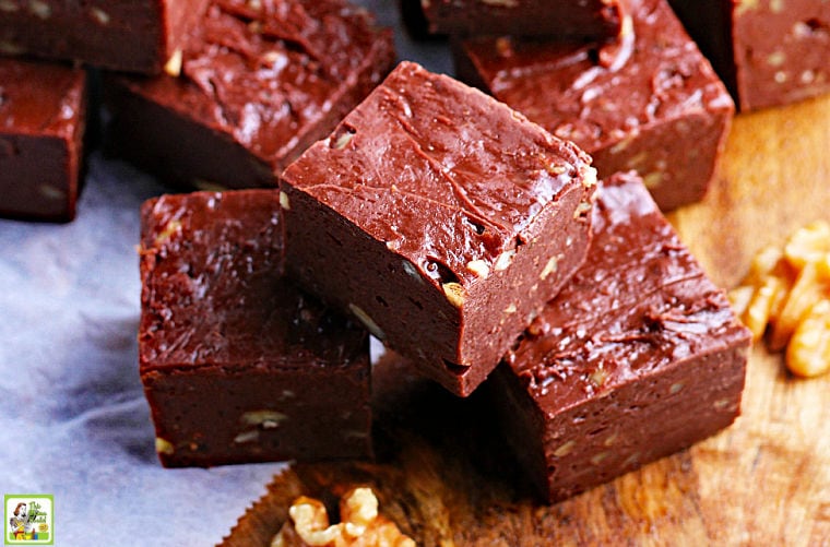 Pieces of chocolate fudge and walnuts on parchment paper.