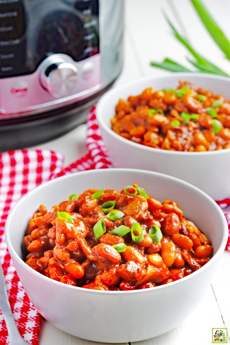 Bowls of baked beans on red and white napkins with a pressure cooker in the background.