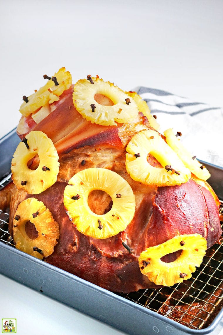 Closeup of a spiral cut ham with cloves and pineapple rings in a baking pan.