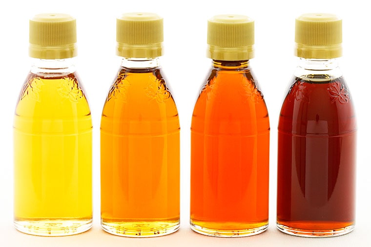 Four varieties of maple syrup in glass bottles.