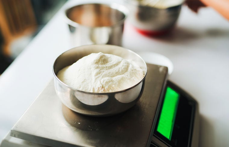 Weighing flour on a digital scale on the kitchen counter.