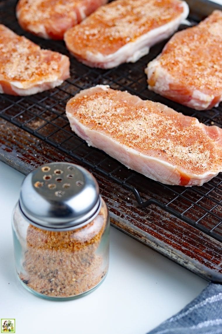 Prepping boneless pork chops with glass bottle filled with dry rub.