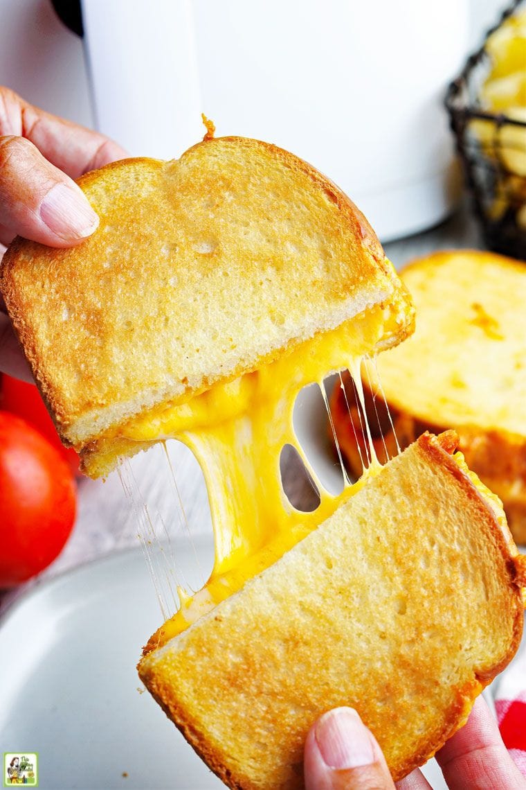 Hands pulling apart a gooey grilled cheese sandwich.