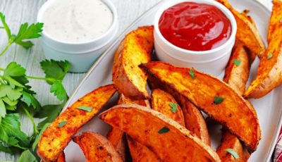 A platter of air fryer sweet potato wedges with small bowls of dipping condiments.