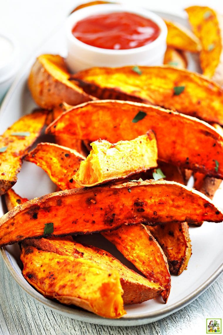 A tray of cooked sweet potatoes cut into wedges with a small bowl of dipping sauce.
